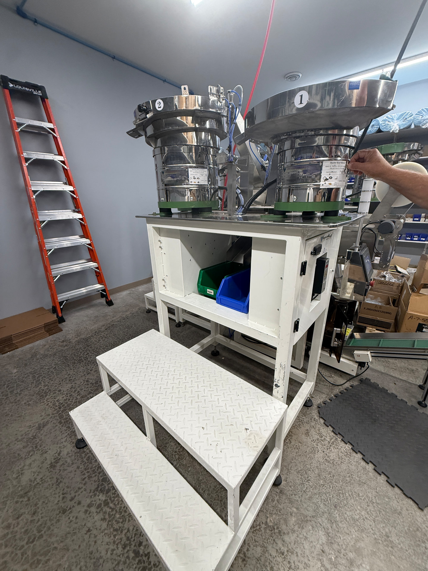 Stainless steel vibratory bowl feeders being set up for a hardware kit changeover